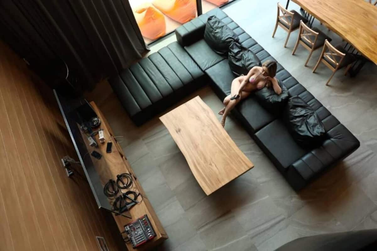 A modern living room with a black sofa, a wooden coffee table, and a sound system.