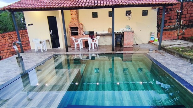 A swimming pool with a tiled deck, a brick barbecue area, and outdoor seating. - Daily or Seasonal Rental in Salinópolis (Salinópolis)