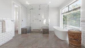 Une salle de bain moderne avec une douche à parois de verre, une baignoire sur pieds et un panier en osier.
