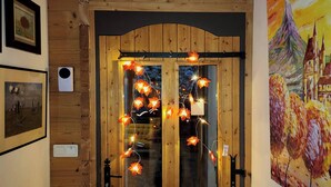 Una porta in legno con pannelli di vetro, decorata con luci a stringa e opere d'arte appese alle pareti.