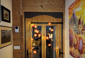 A wooden door with glass panels, adorned with string lights, and framed artwork on the walls. - Chalet Retreat Private Self Contained 4 to 6 Person Mountain Views Own Terrace (Les Villards-sur-Thônes)