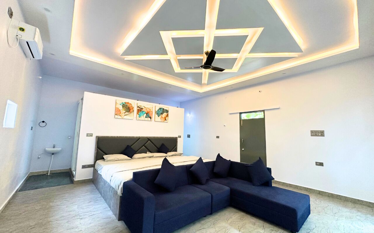 Une chambre moderne avec un lit, un canapé, un ventilateur de plafond et des œuvres d’art accrochées au mur.