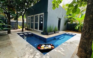 Una casa moderna con piscina, una mesa de comedor con comida y un ventanal grande.