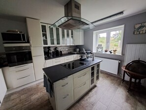 A modern kitchen with white cabinets, a black countertop, and a built-in stove. - Vacation home/group house for up to 14 people Holl & Boll Pet-friendly (Clausthal-Zellerfeld)