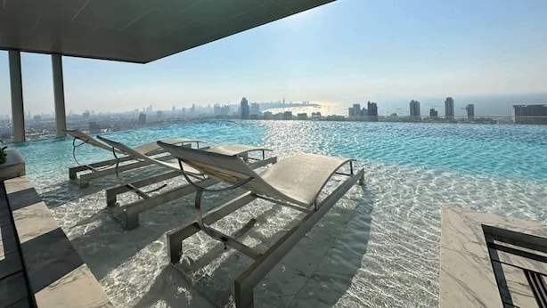 Ein Pool auf dem Dach mit Liegestühlen, freier Blick auf den Stadtpanoramahimmel und ein modernes architektonisches Design.