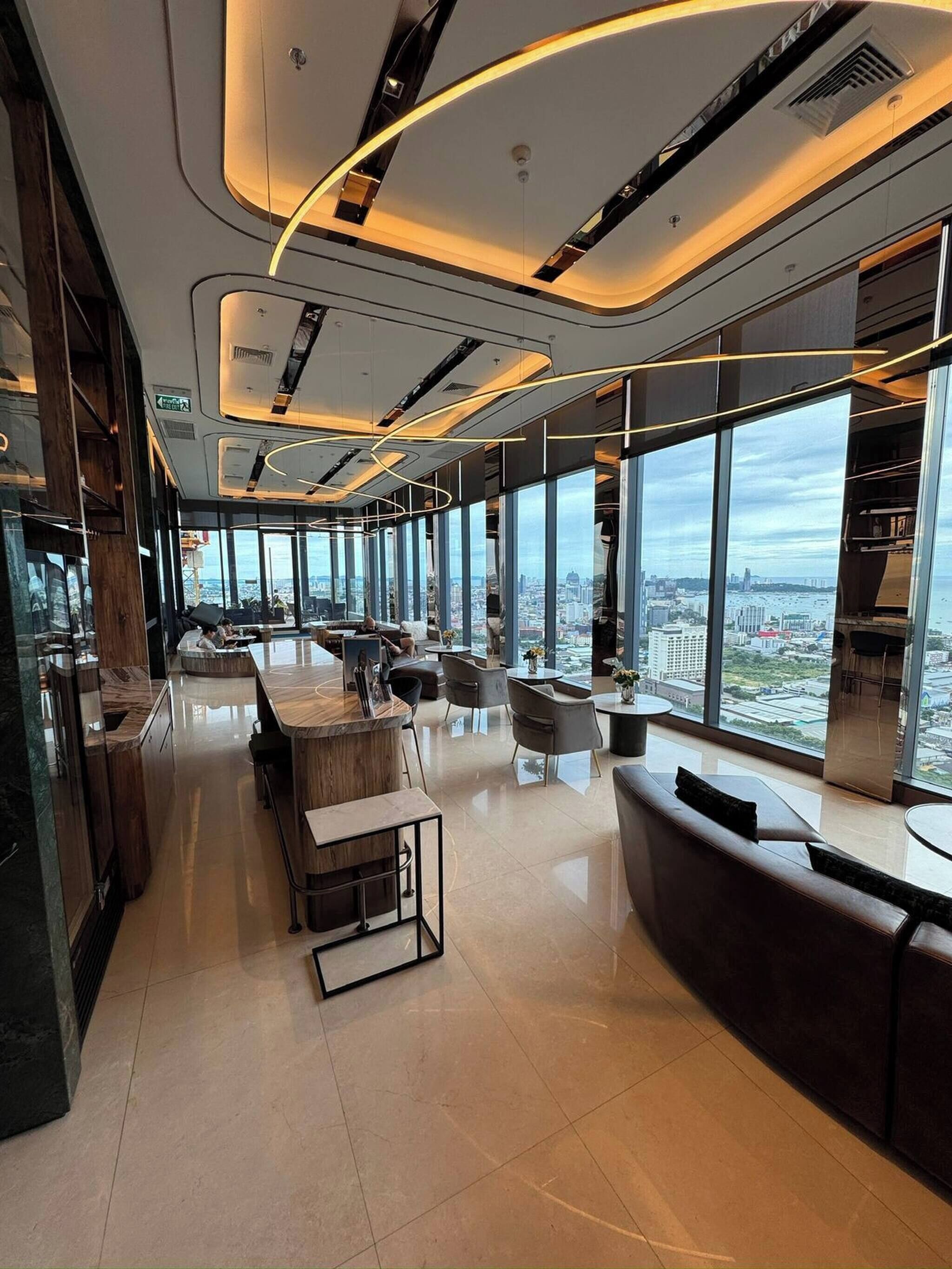 A modern interior with a bar area, seating, and large windows offering city views.