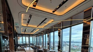 Ein modernes Interieur mit Barbereich, Sitzgelegenheiten und großen Fenstern mit Blick auf die Stadt.