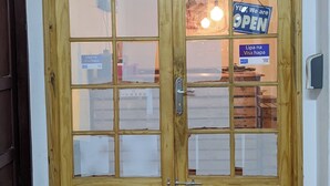 A wooden double door with glass panels, a sign indicating 'The Train's House Restaurant,' and a 'OPEN' sign. - The Hub Train House Exotic Roots (Zanzibar)