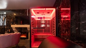 Ein modernes Interieur mit Kamin, einem roten Beleuchtungselement und einem rosafarbenen Sessel.
