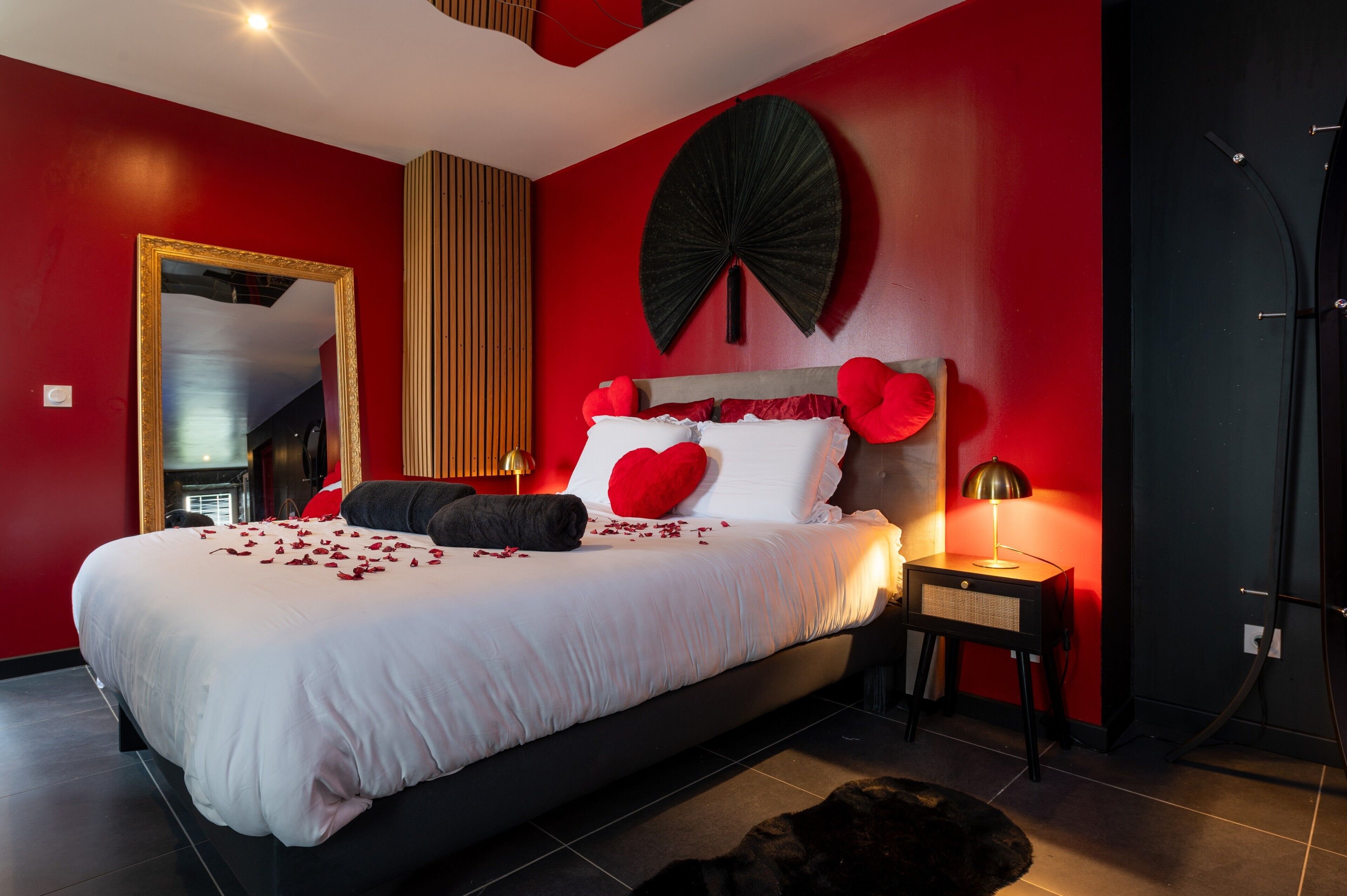 A bedroom with a bed, a mirror, a wall fan, and a nightstand.