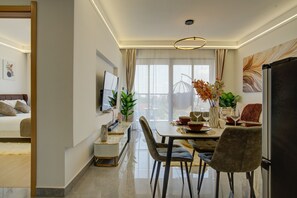 A modern dining area with a table set for four, a sofa, and a TV mounted on the wall. - Luxurious apartment in Lavington Nairobi (Nairobi)
