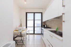 A compact kitchen with a dining area, a black-framed sliding door, and a white countertop. - Large Duplex with private Terrace Gluck Milan (Milano)