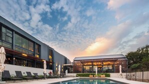 Ein modernes Hotel mit Pool, Liegestühlen und Sonnenschirmen.