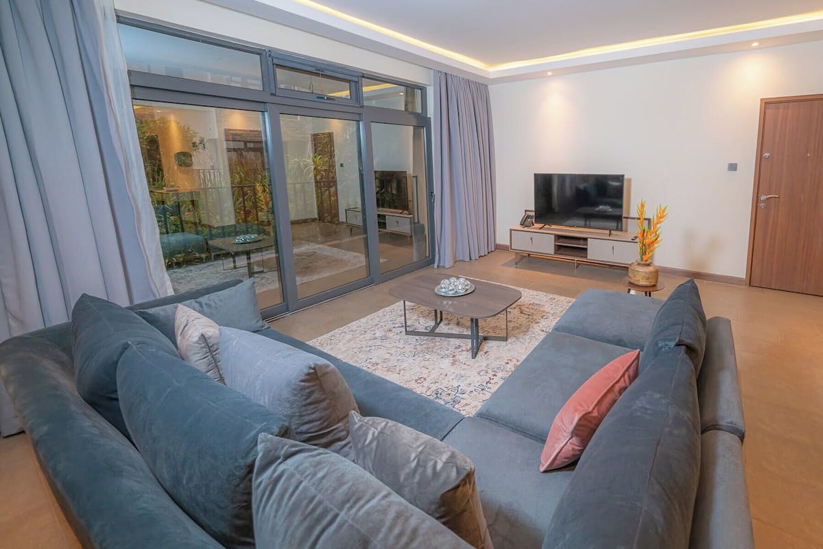 Una sala de estar moderna con un sofá grande, una mesa de centro y un televisor de pantalla plana.