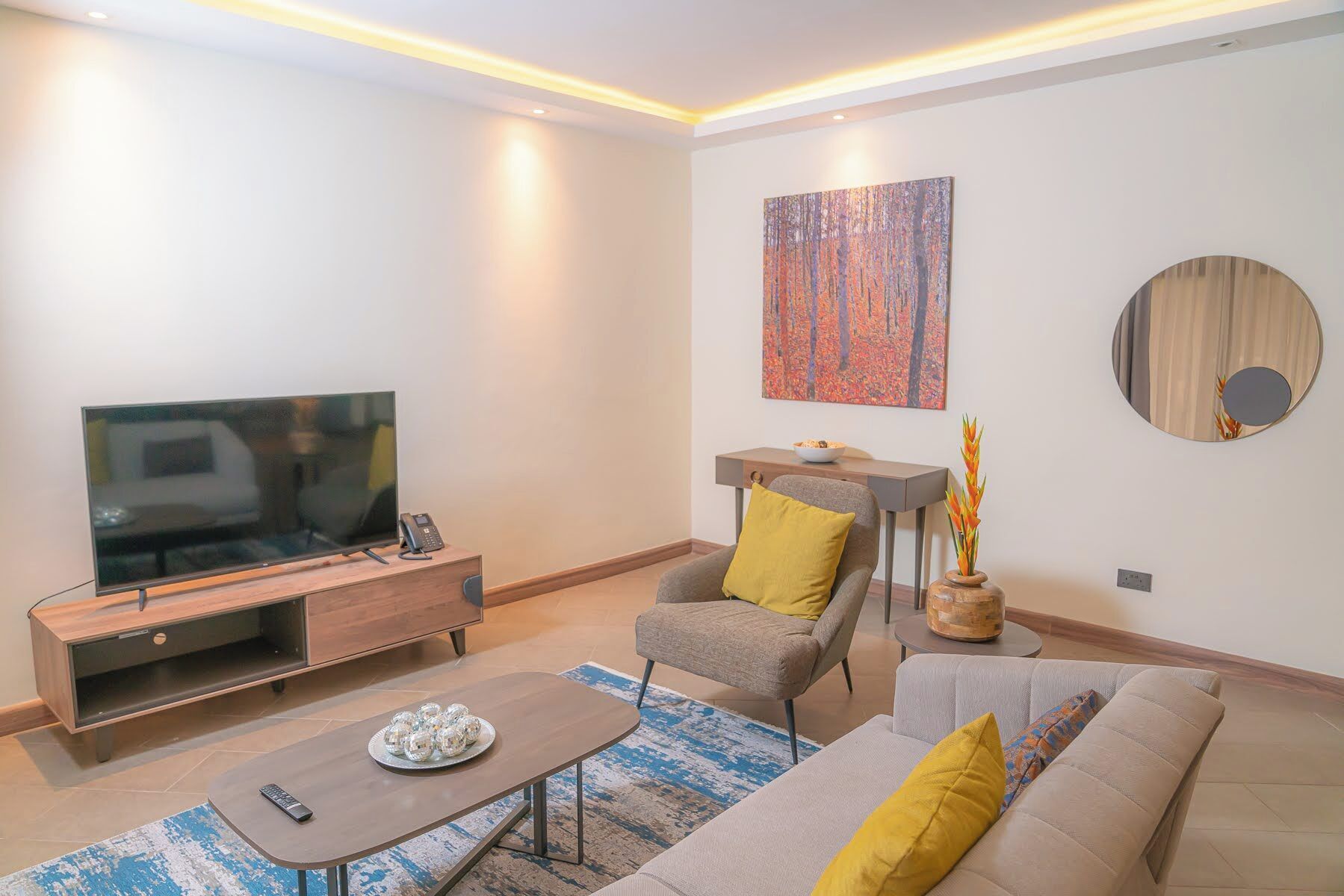 A modern living room with a flat-screen TV, a wooden entertainment unit, a sofa, a coffee table, and a decorative vase.