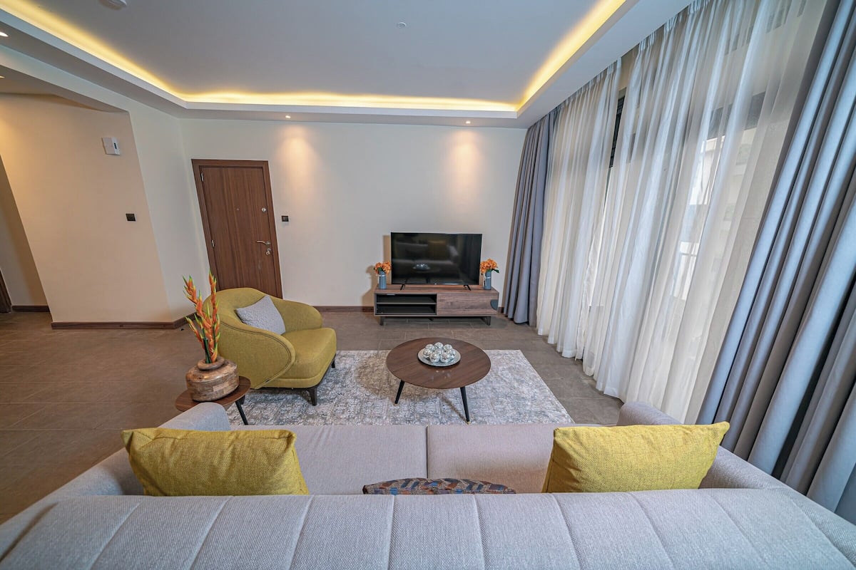Una sala de estar moderna con un sofá, sillones, un televisor y una mesita de centro.