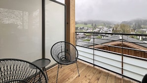 En balkon med udsigt over en by, en stol og et bord.