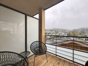 Ein Balkon mit Blick auf eine Stadt, ein Stuhl und ein Tisch.