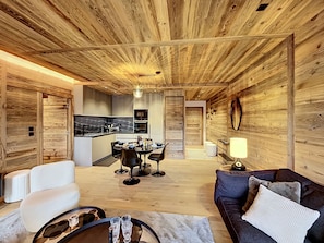 Ein geräumiger Wohnbereich mit Holzbalkendecke, einem Esstisch mit Stühlen, einer Couch und einem Couchtisch.