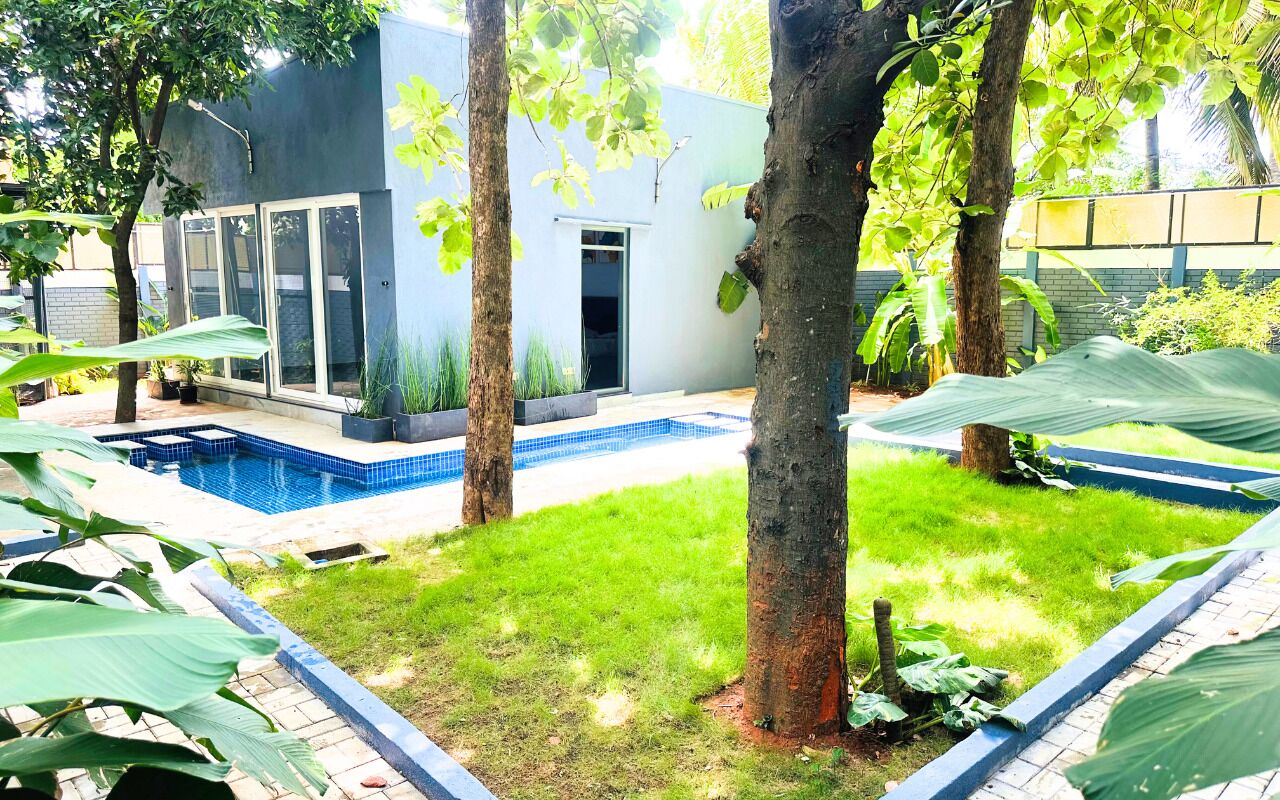 A modern house with a swimming pool, surrounded by trees and a well-maintained lawn.