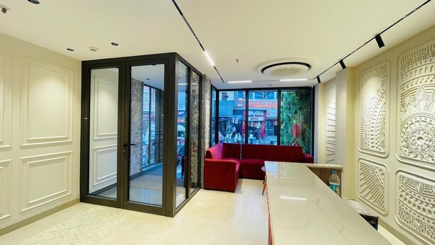 Un hall d’hôtel moderne avec une cloison en verre, un canapé rouge et des motifs complexes sur les murs.