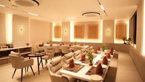 A modern dining area with round tables, cushioned chairs, and decorative wall panels. - HARI VILAAS KASHI (Varanasi)