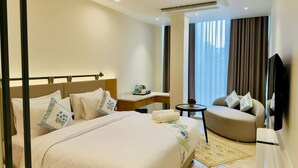 Une chambre d’hôtel avec un lit, un canapé, une télévision, un bureau et une fenêtre avec des rideaux.