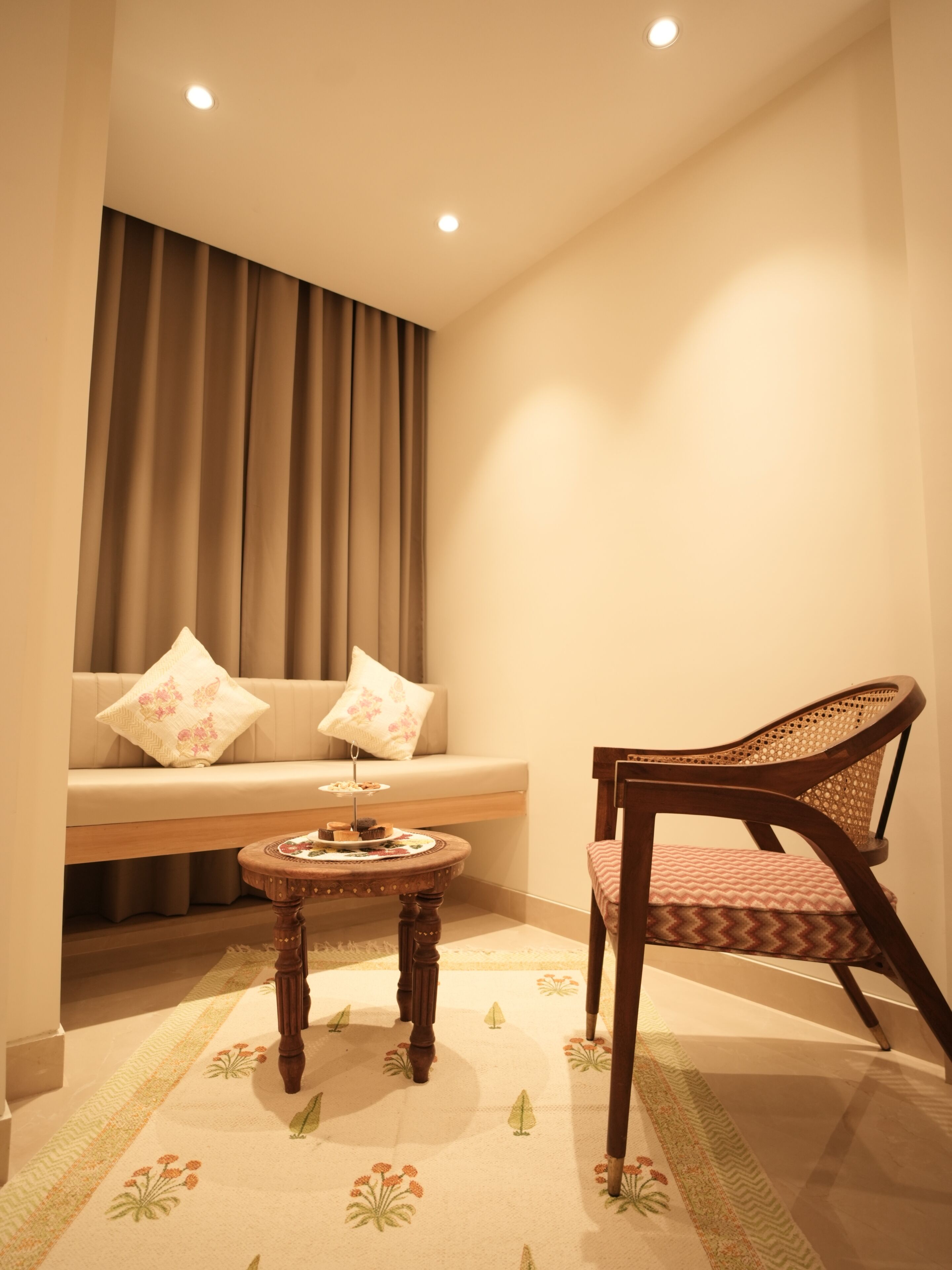 A cozy living area with a sofa, a wooden chair, and a small round table with a tray of snacks.