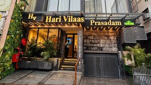Un hôtel appelé Hari Vilas, doté d’une façade moderne en verre, d’une entrée en pierre et d’une enseigne indiquant qu’il s’agit d’un restaurant végétarien.