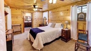 Una stanza con rivestimento in legno, un letto, un comodino, una sedia, una scrivania e una ventola a soffitto.