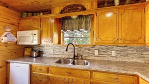 Cucina con mobili in legno, lavello in acciaio inossidabile, forno a microonde ed elettrodomestici.