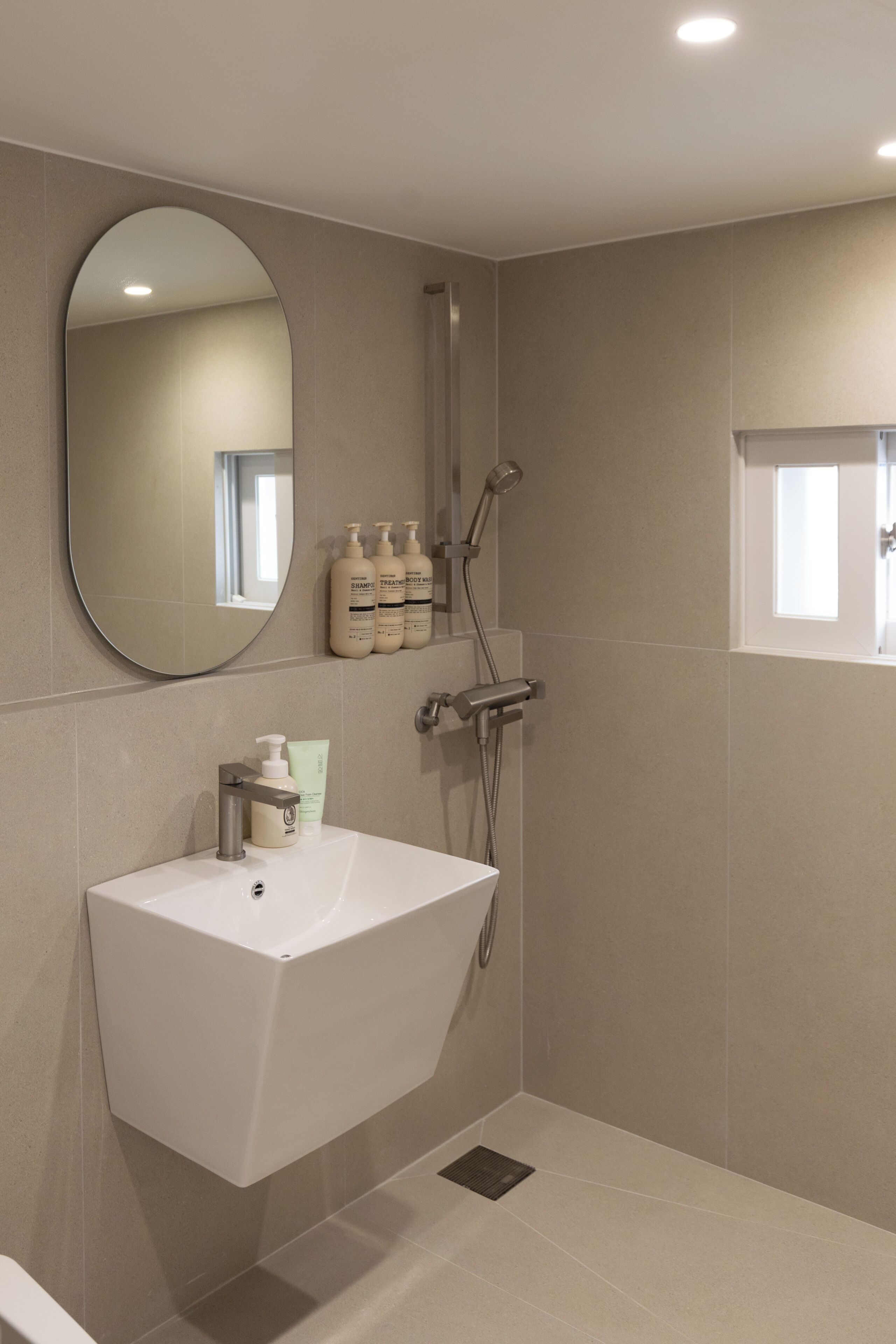 A modern bathroom with a white sink, a mirror, and a shower.