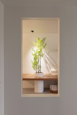 A potted plant in a recessed shelf with a white cushion and a basket below. - Lua Hotel (Seoul)