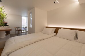 A hotel room with a bed, a desk, a chair, and a potted plant. - Lua Hotel (Seoul)