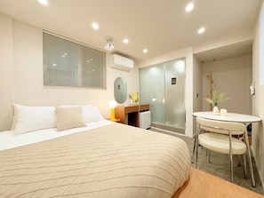 A hotel room with a bed, bedside table, lamp, and a small table with chairs. - Lua Hotel (Seoul)