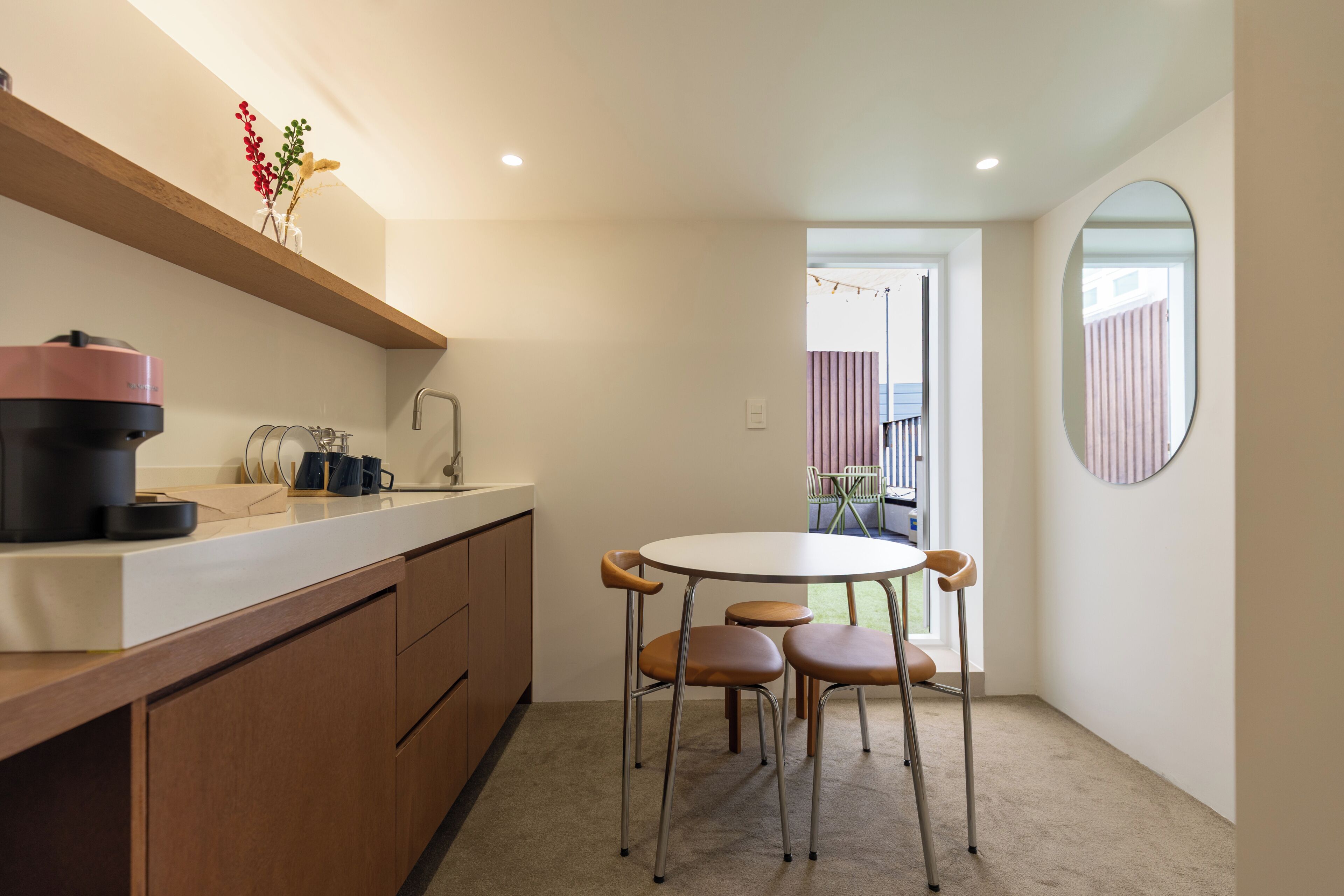 A compact kitchen with a coffee machine, a sink, and a dining area with a table and chairs.