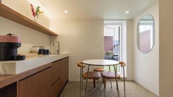 A compact kitchen with a coffee machine, a sink, and a dining area with a table and chairs.