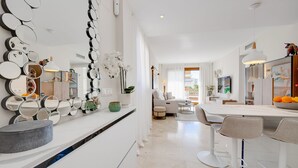 Une cuisine moderne dotée d’un îlot central, d’un coin repas avec des tabourets de bar et d’un salon avec un canapé et une table basse.