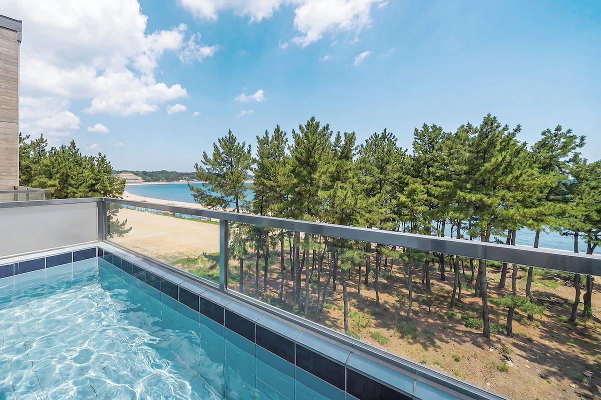 Una piscina con vistas a la playa y árboles.