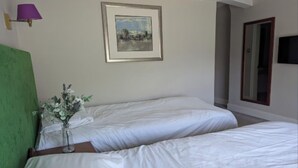 A hotel room with two beds, a framed picture on the wall, a vase with flowers, and a television mounted on the wall. - Standard family room for 4(2A+2C) (Burton-On-Trent)