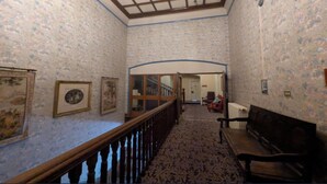 A hallway with patterned wallpaper, a wooden staircase, and a bench. - Standard family room for 4(2A+2C) (Burton-On-Trent)