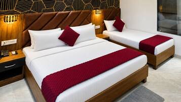 Habitación de hotel con dos camas, un revestimiento mural de estampado geométrico, un cabecero moderno, lámparas de noche, un equipo de aire acondicionado integrado y una mesita de noche pequeña con un teléfono.