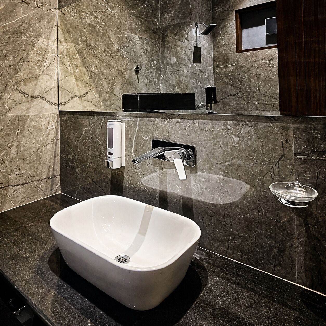A bathroom with a large, white vessel sink, a handheld showerhead, and a built-in soap dispenser.