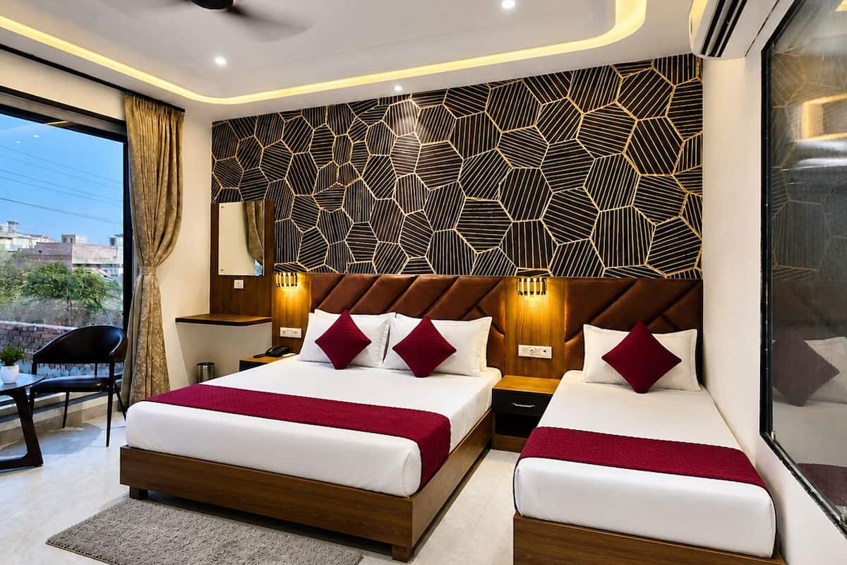 A modern hotel room with two beds, a ceiling fan, and a geometric-patterned wall.