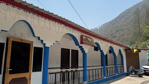 Un edificio con techo rojo, detalles en azul y un letrero en idioma local.