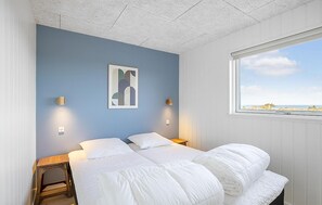 Ein Schlafzimmer mit einem Bett, zwei Nachttischen, einer Wandleuchte und einem Fenster mit Blick.