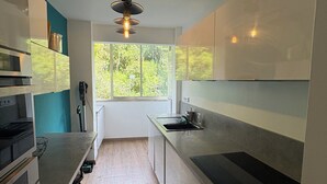 Una cocina moderna con un ventanal grande, suelo de madera y estufa empotrada.