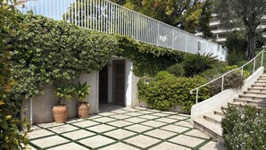 Un patio empedrado con barandilla blanca, macetas y una escalera.