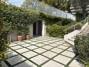 Ein gepflasterter Innenhof mit weißer Brüstung, Kübelpflanzen und einer Treppe.