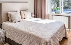 A neatly made bed with a quilted bedspread, a headboard, and several pillows.